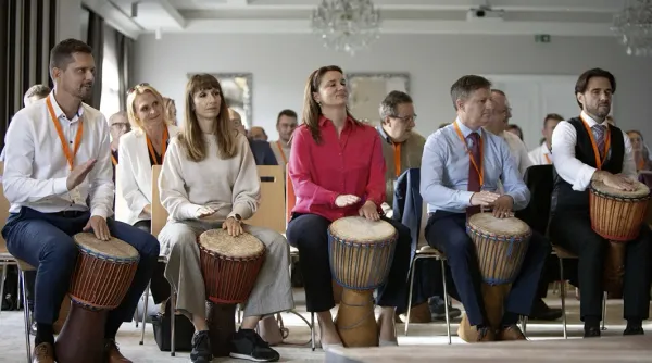 Účastníci firemní akce s djembe bubny v konferenčním sále