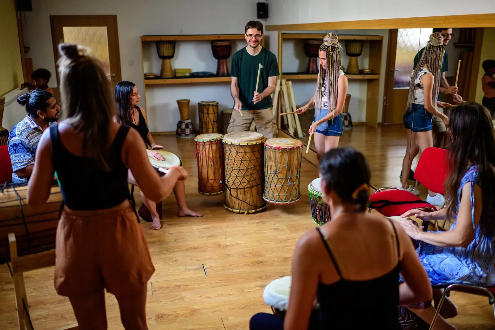 Workshop afrického bubnování - lektor učí účastníky v kruhu