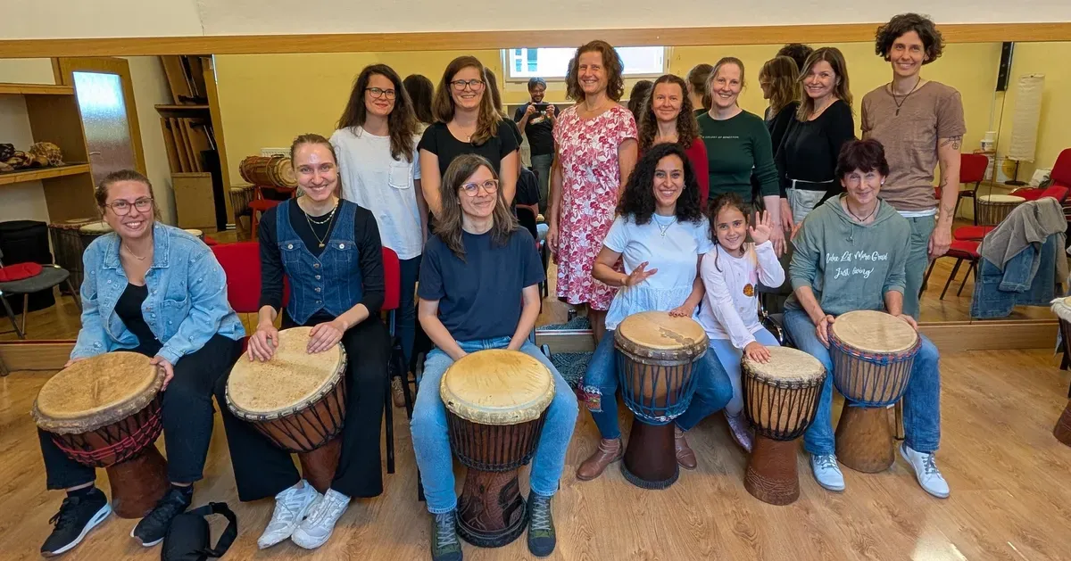 Účastníci workshopu hrají na djembe a basové bubny